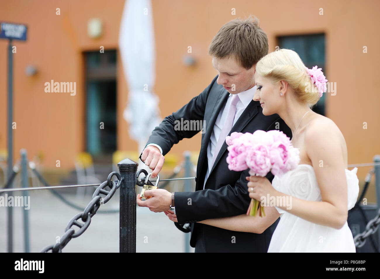 Beautiful bride and groom hanging lucky lock on a bridge Stock Photo ...