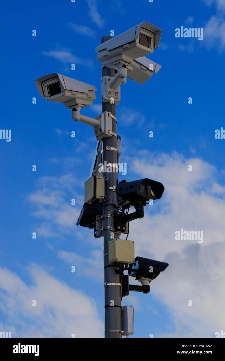 Different types of CCTV security cameras fixed on a pole on a blue sky background - security, big brother concept Stock Photo