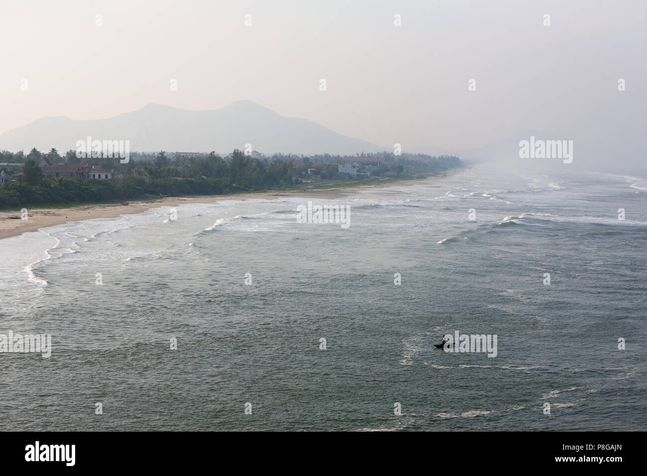 Lone fisherman braves the breaking waves in a canoe in Lăng Cô Bay (Cửa Biển Lăng Cô) Phú Lộc, Viet Nam Stock Photo