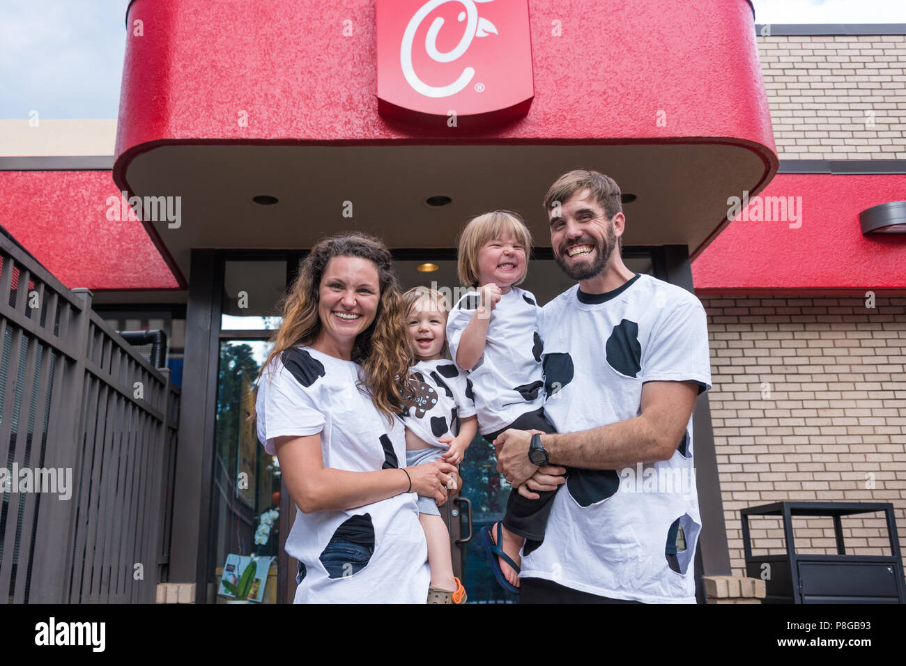 A happy family with their homemade cow outfits for Cow Appreciation Day at Chick-fil-A, America's top-rated quick service restaurant. (USA) Stock Photo