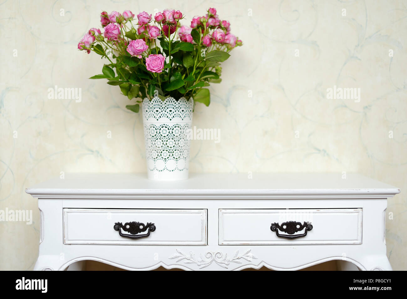 White vase full of pink roses on a counter Stock Photo