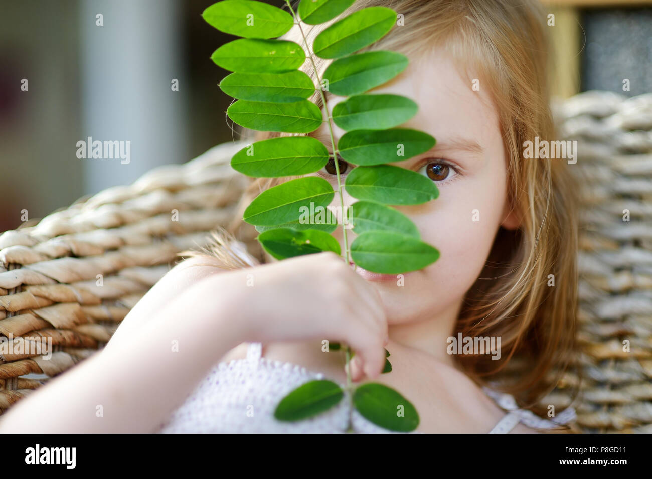 Adorable little girl hiding behind a leaf outdoors Stock Photo - Alamy