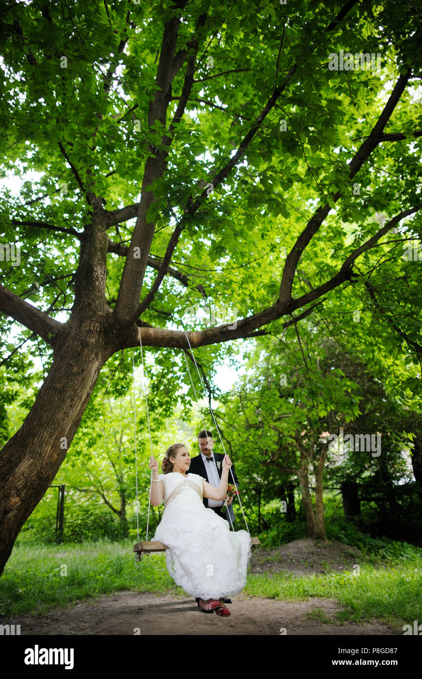 Beautiful bride and groom swinging in a park Stock Photo - Alamy