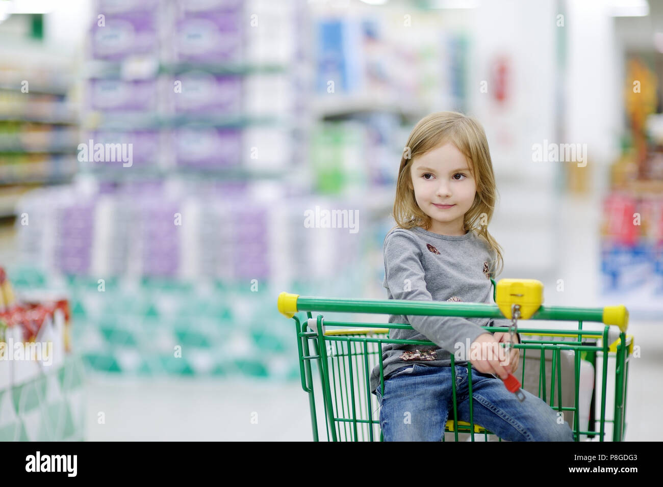 Adorable little girl sitting in shopping cart Stock Photo - Alamy