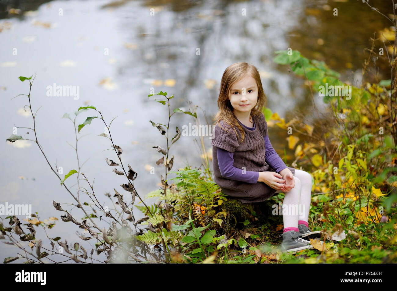 Adorable little girl playing by a river on autumn day Stock Photo - Alamy