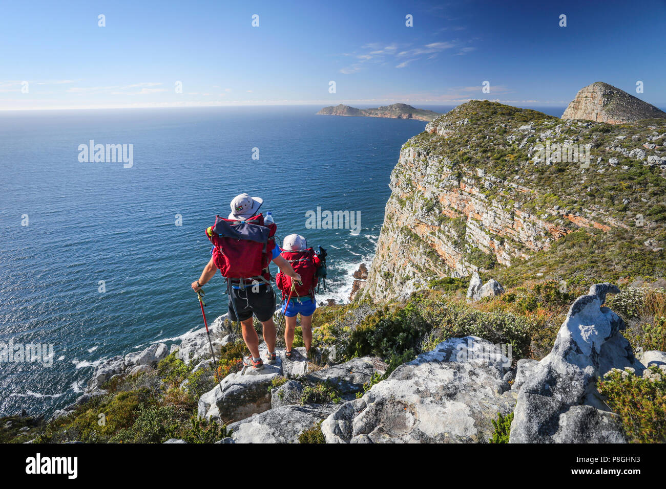 Man and woman hikers enjoying the view over the sea fro ma high mountain in Cape Point National Park, South Africa. Stock Photo