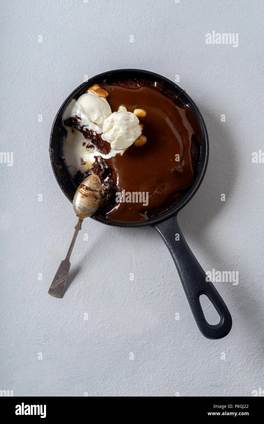 Brownie in a skillet with a scoop of vanilla ice cream, salted caramel and roasted peanuts Stock Photo