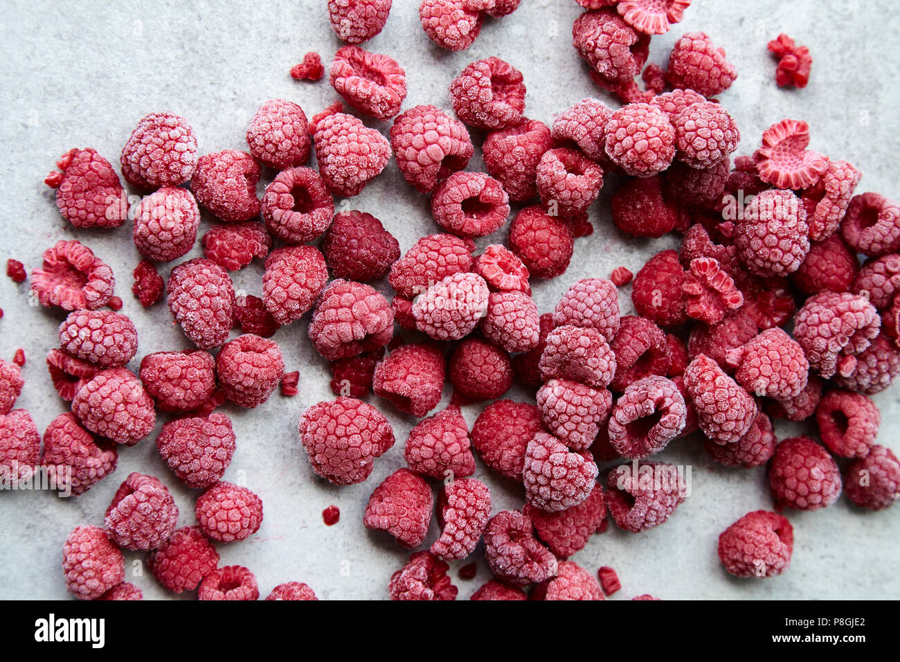 Frozen raspberries on grey stone background Stock Photo - Alamy