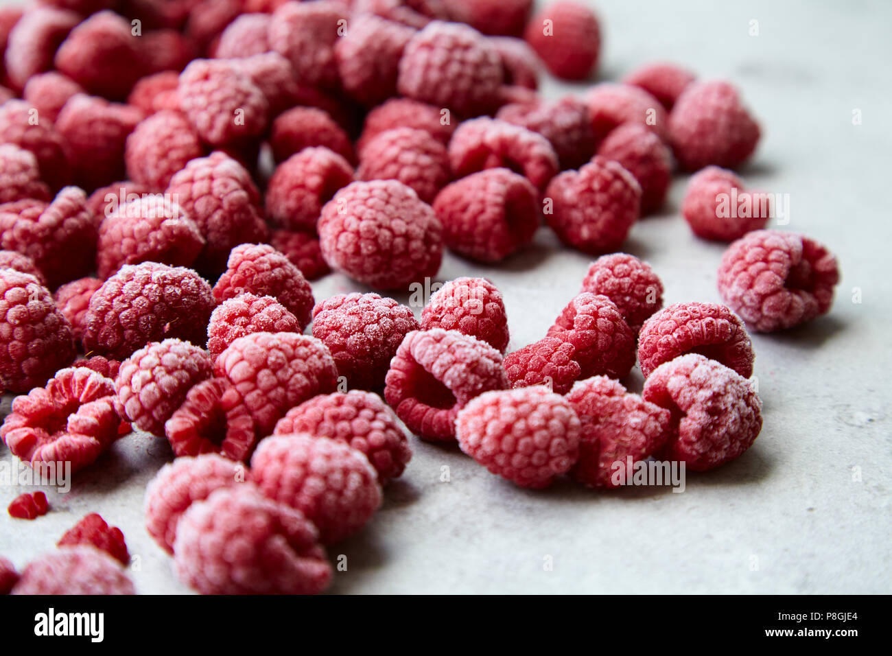 Frozen raspberries on grey stone background Stock Photo - Alamy