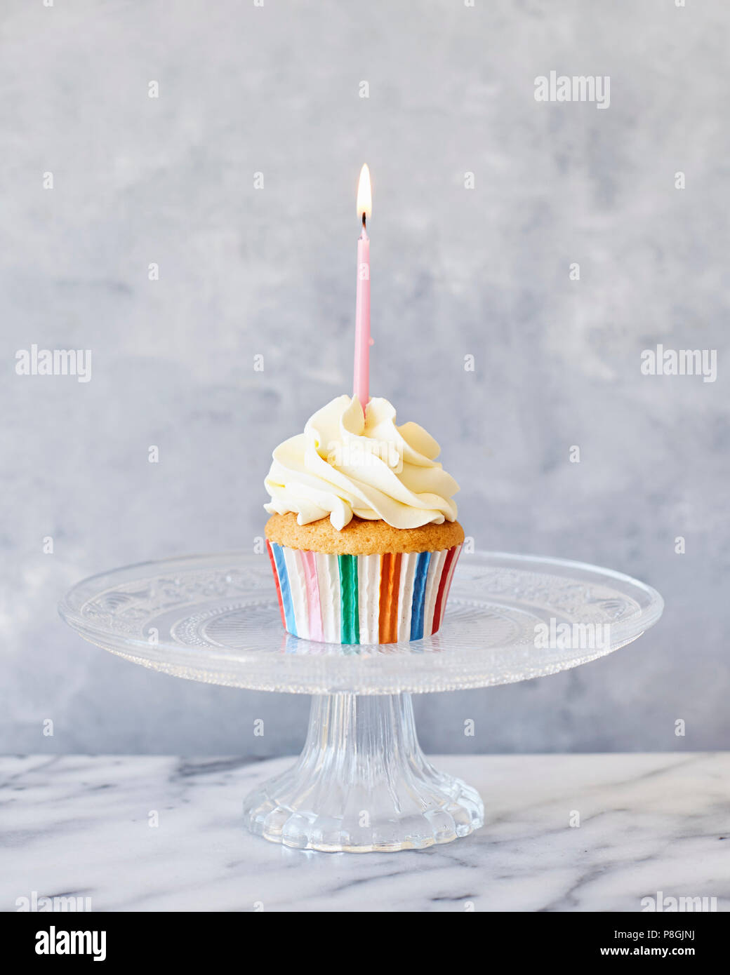 Party cupcake with pink candle on cake stand Stock Photo Alamy