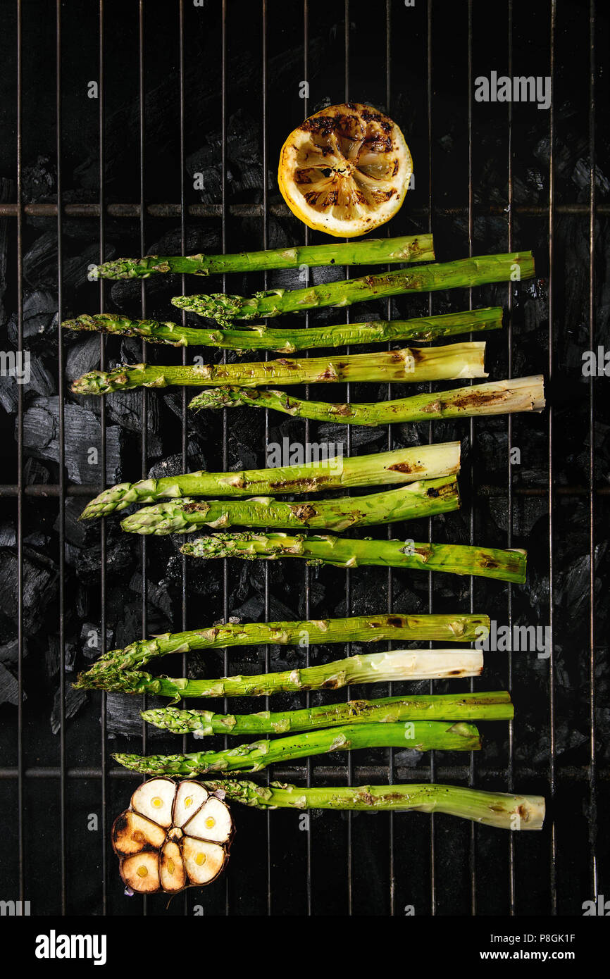 Grilled vegetables green asparagus, garlic, lemon on bbq grill rack