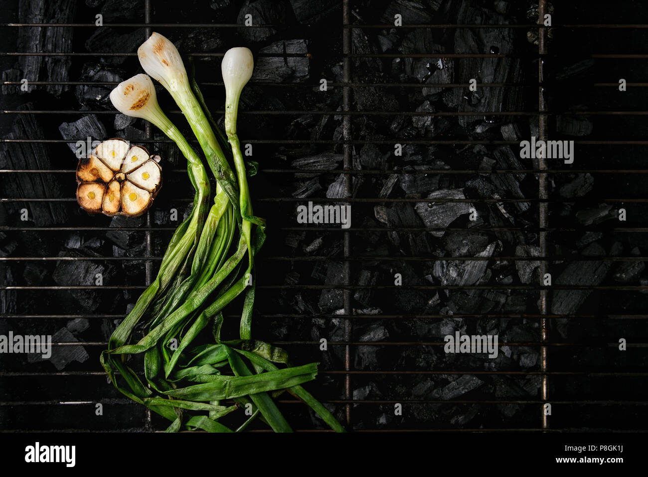 Grilled vegetables spring onion and garlic on bbq grill rack over