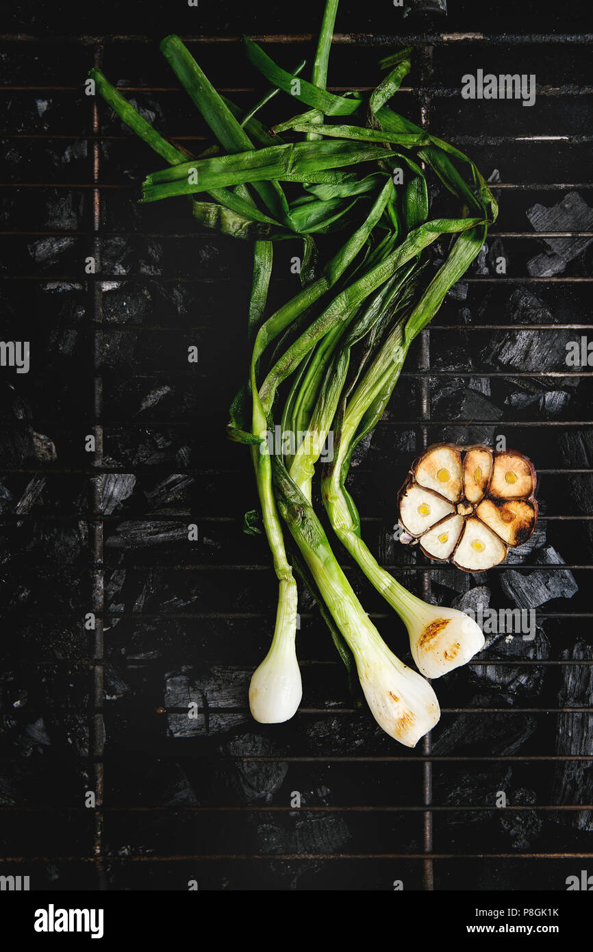 Grilled vegetables spring onion and garlic on bbq grill rack over