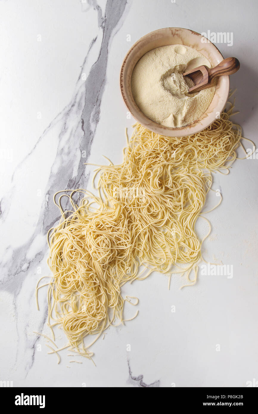 Homemade italian uncooked pasta spaghetti with bowl of semolina flour