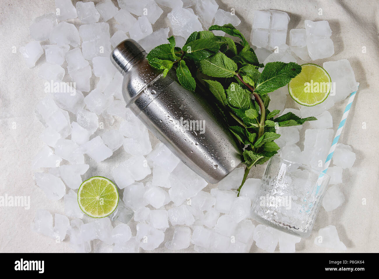 Cocktail making concept. Silver shaker, mint, sliced lime, cocktail