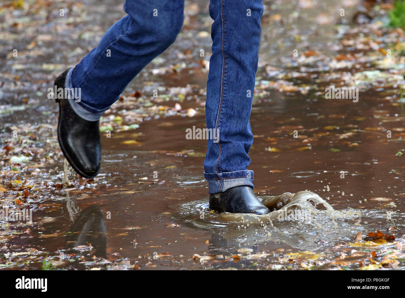 Hannover, Germany, closeup, woman in rubber boots running through a deep puddle Stock Photo