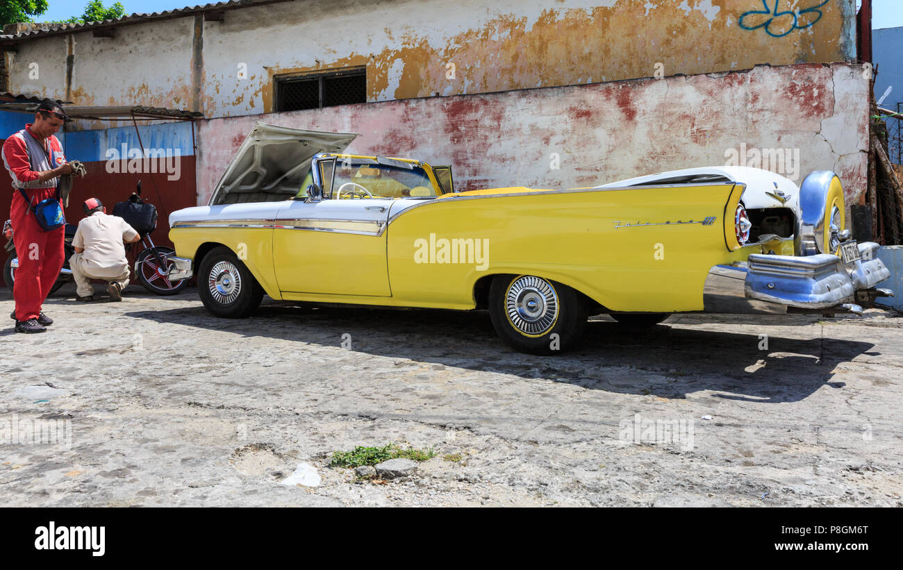 1957 Ford Fairlane 500 Skyliner convertible in yellow, American classic car being cleaned at a garage in Havana, Cuba Stock Photo