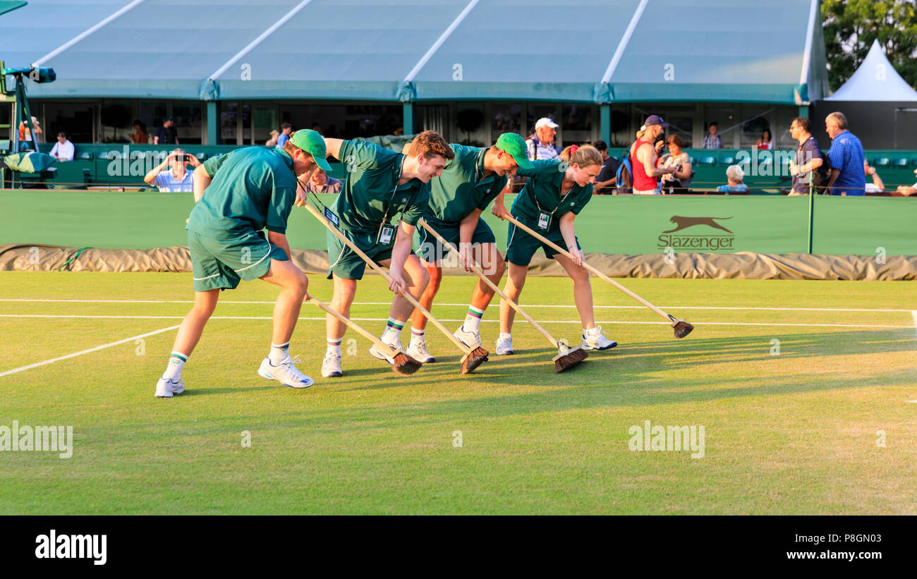 Court maintenance attendants swipe a Wimbledon grass court to preserve