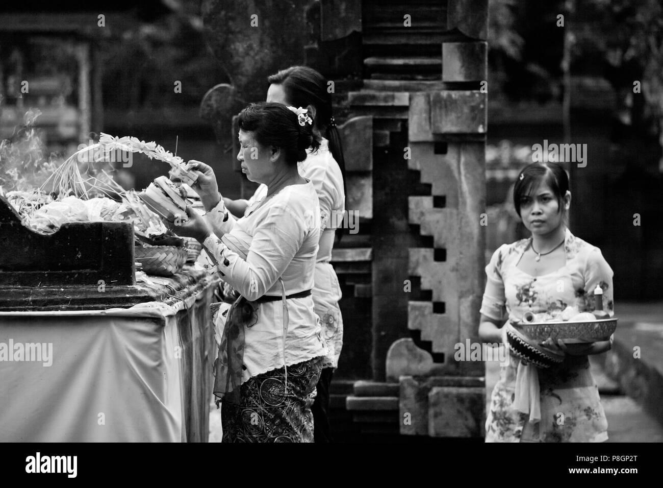 BALINESE WOMEN make offerings at  PURA TIRTA EMPUL a Hindu Temple complex and cold springs with healing waters -  TAMPAKSIRING, BALI, INDONESIA Stock Photo