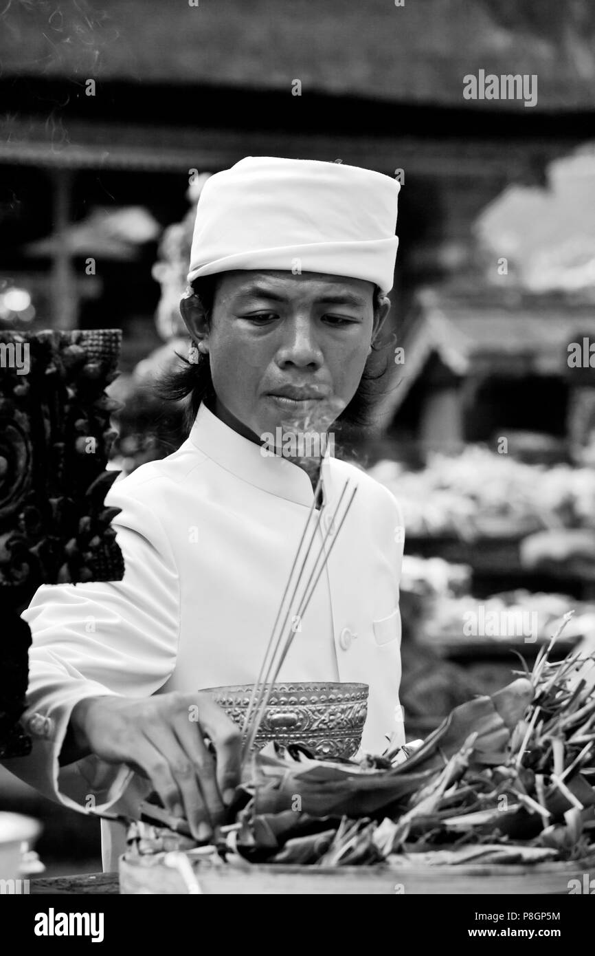 A Hindu priest offers incense at the PURA TIRTA EMPUL TEMPLE COMPLEX during the GALUNGAN FESTIVAL -  TAMPAKSIRING, BALI, INDONESIA Stock Photo