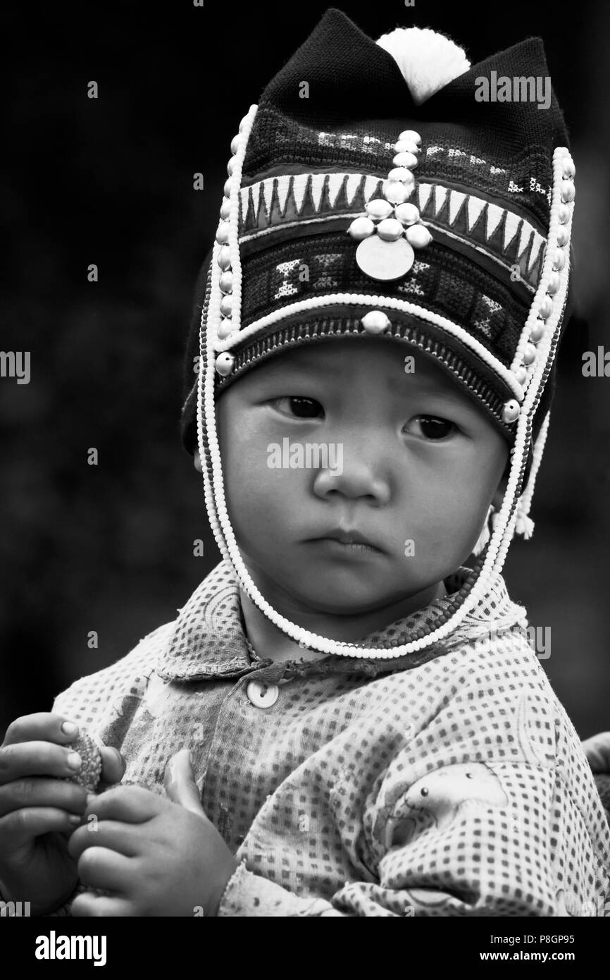 A baby girl of the AKHA tribe wears a childs headdresse made of beads, silver and hand loomed cotton -  village near KENGTUNG or KYAINGTONG, MYANMAR Stock Photo