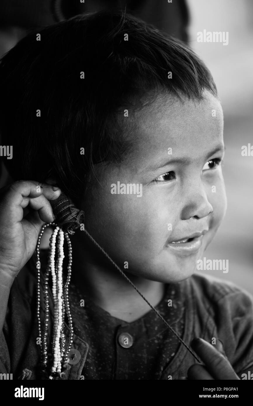 A child from the ANN TRIBE plays with bead work in a village near KENGTUNG or KYAINGTONG - MYANMAR Stock Photo