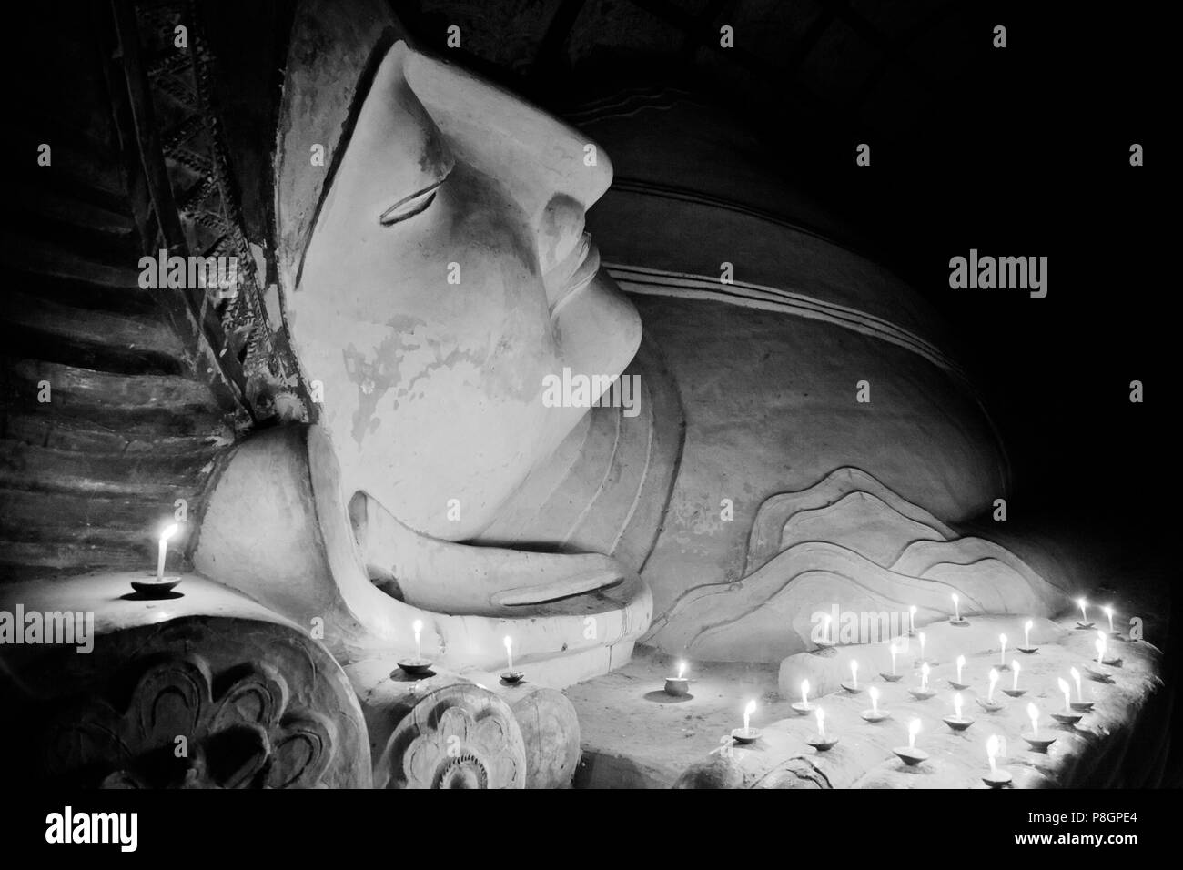 Candle offerings to 11th century reclining BUDDHA at SHINBINTHAHLYAUNG TEMPLE - BAGAN, MYANMAR Stock Photo