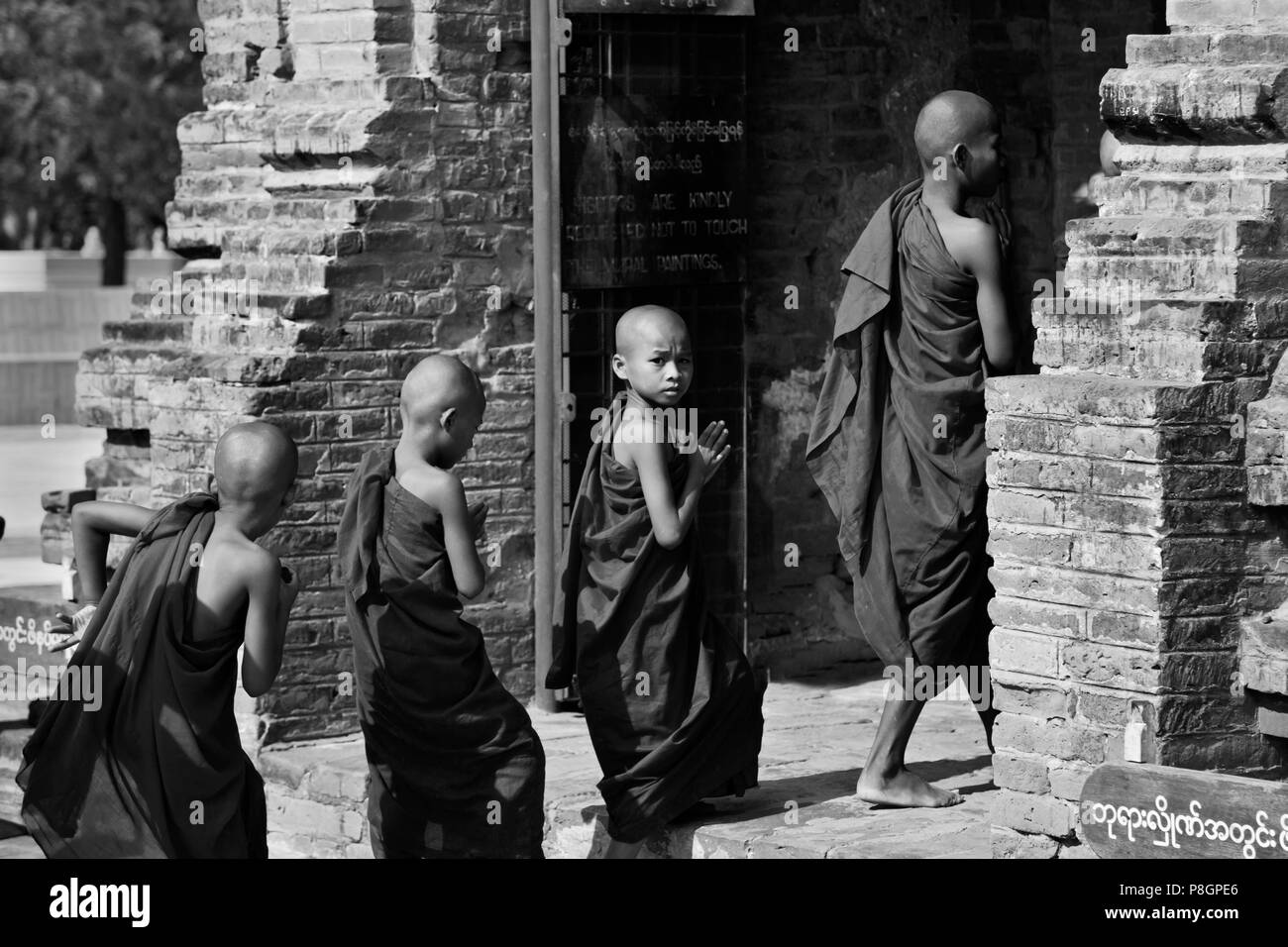 Young BUDDHIST MONKS enter one of the stupas of the ALO PYI GROUP  - BAGAN, MYANMAR Stock Photo