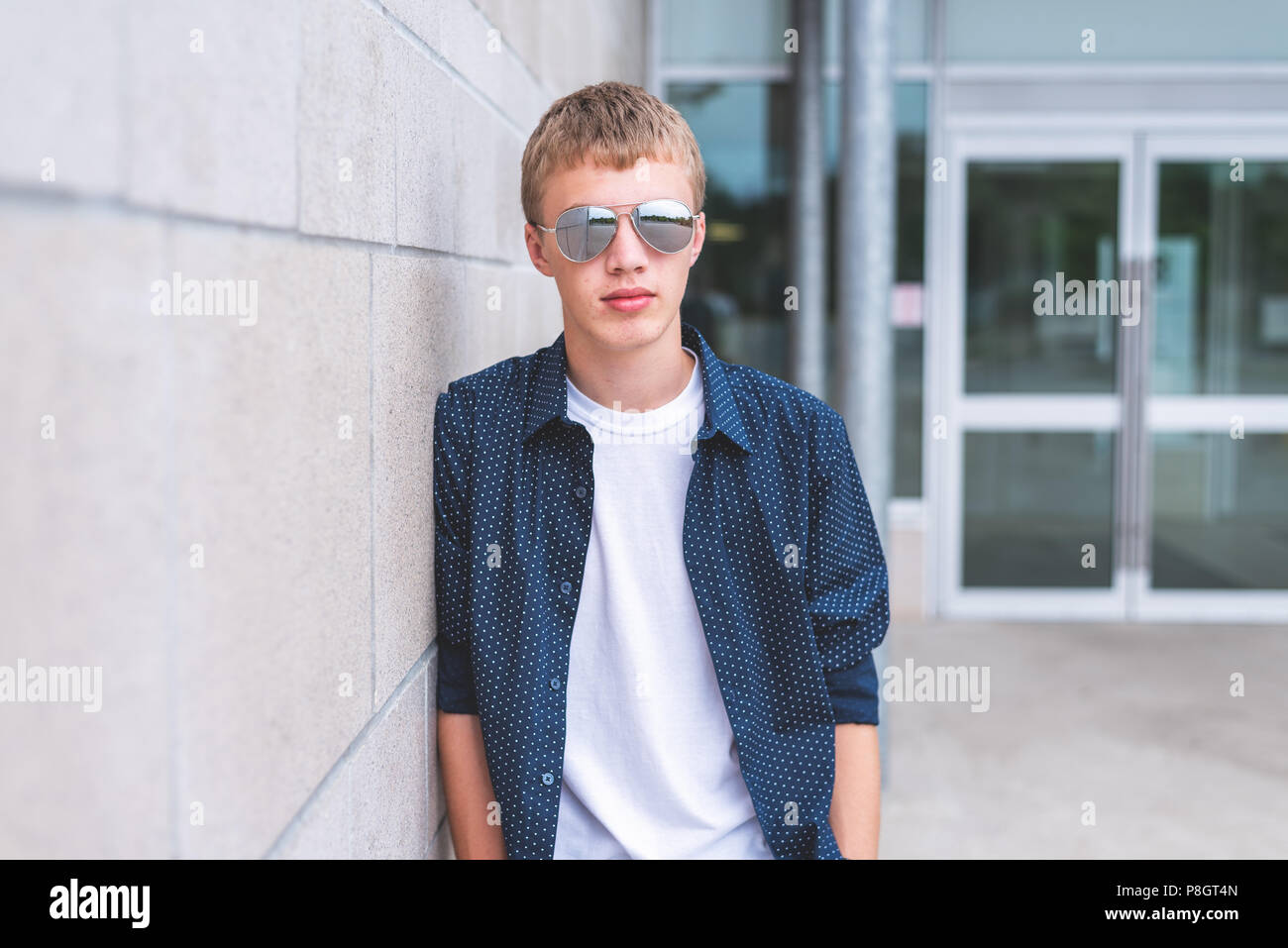 Serious teen wearing sunglasses and leaning against a brick wall Stock ...