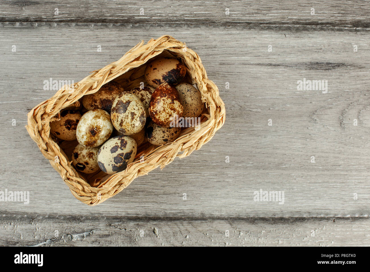 Table top view of quail eggs placed in small rectangular basket. Stock Photo