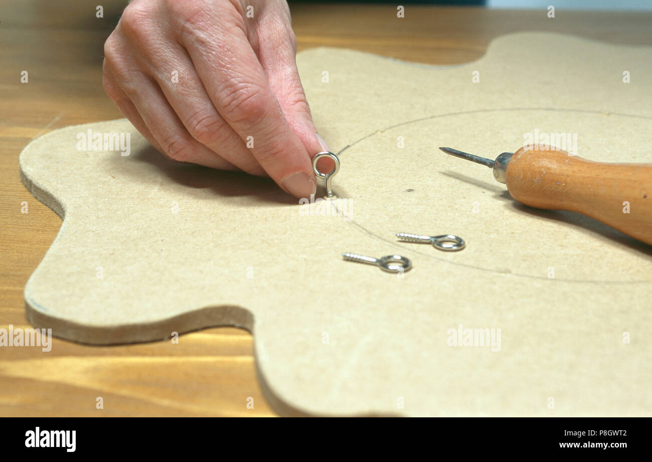 Close Up Of Hands Attaching Hooks To Mdf Ceiling Rose For