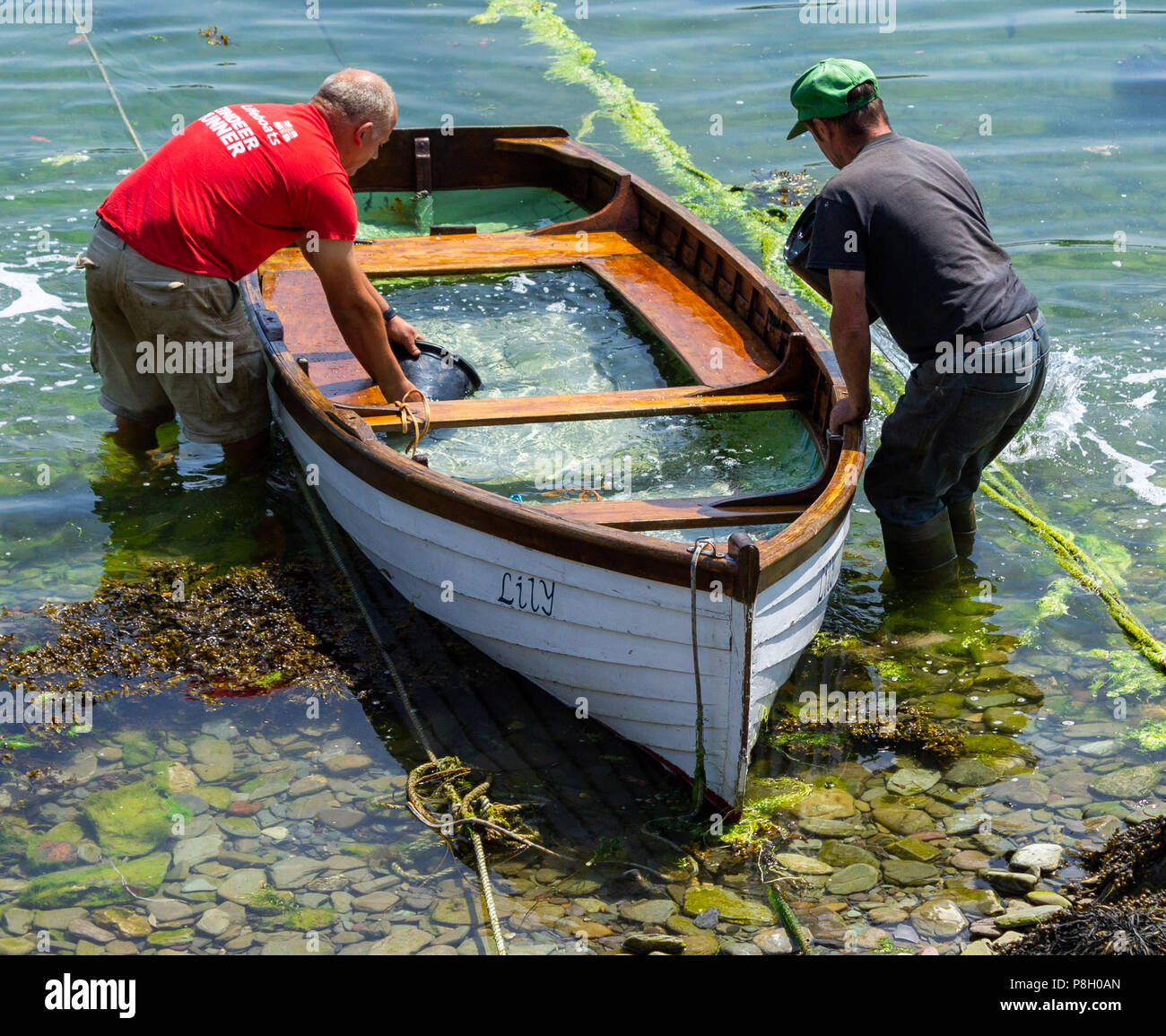 West Cork, Ireland. 11th July, 2018. The constant scorching sun has caused the clinker built wooden planks of the boat to shrink allowing seawater in. Leaving the hull flooded for a few days allows the wood to swell and become water tight, but it still needs bailing out!!  Credit: aphperspective/Alamy Live News Stock Photo