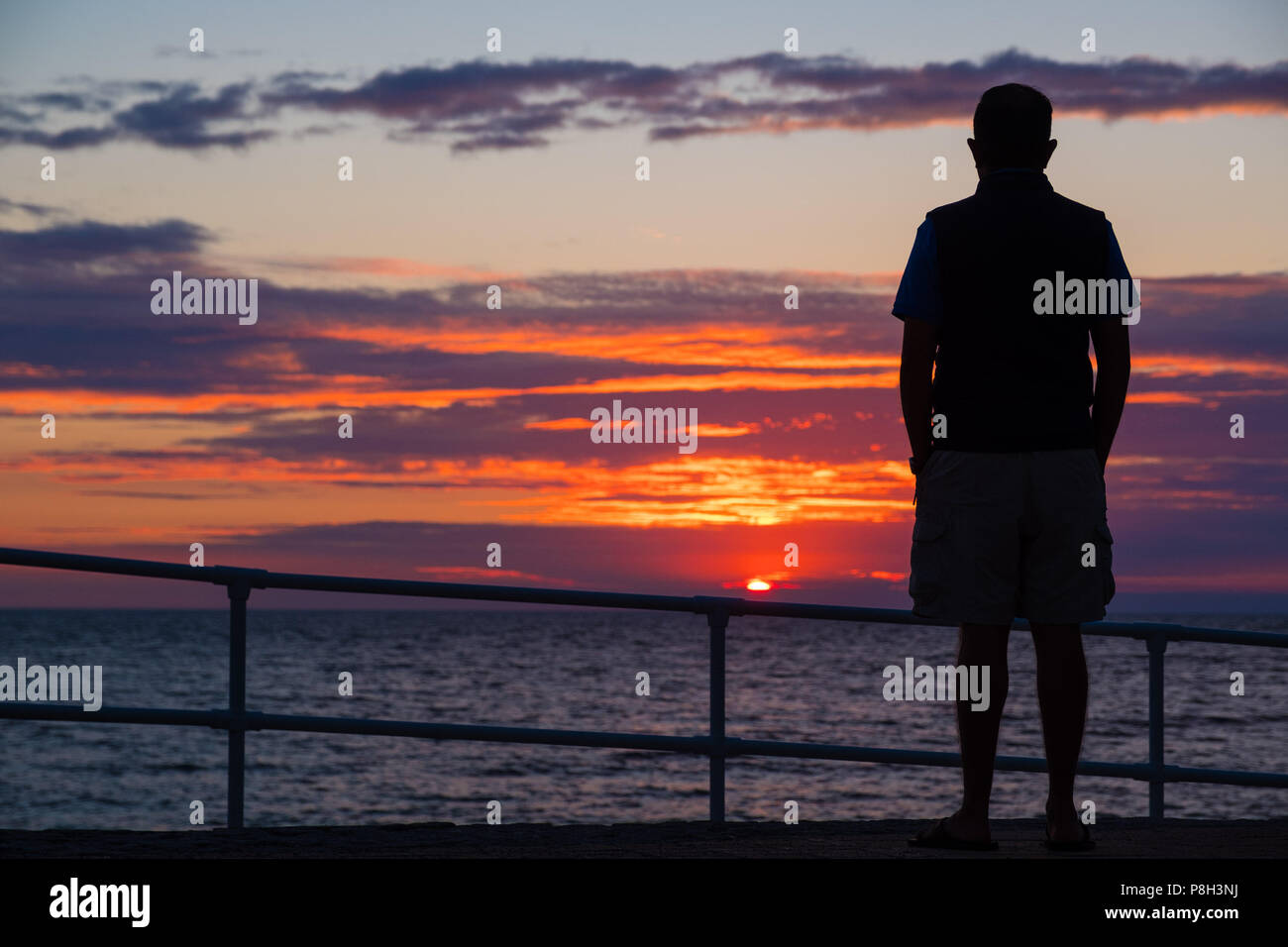 Aberystwyth Wales UK, 11 July 2018. UK Weather:  A man watches as the sun sets on yet another England football World Cup dream, with the team being beaten 2-1 by Croatia after extra time in the semi final. The years of hurt continue for a side who last won the tropy in 1966, and have not been further than the semi final since  then  photo © Keith Morris / Alamy Live News Stock Photo