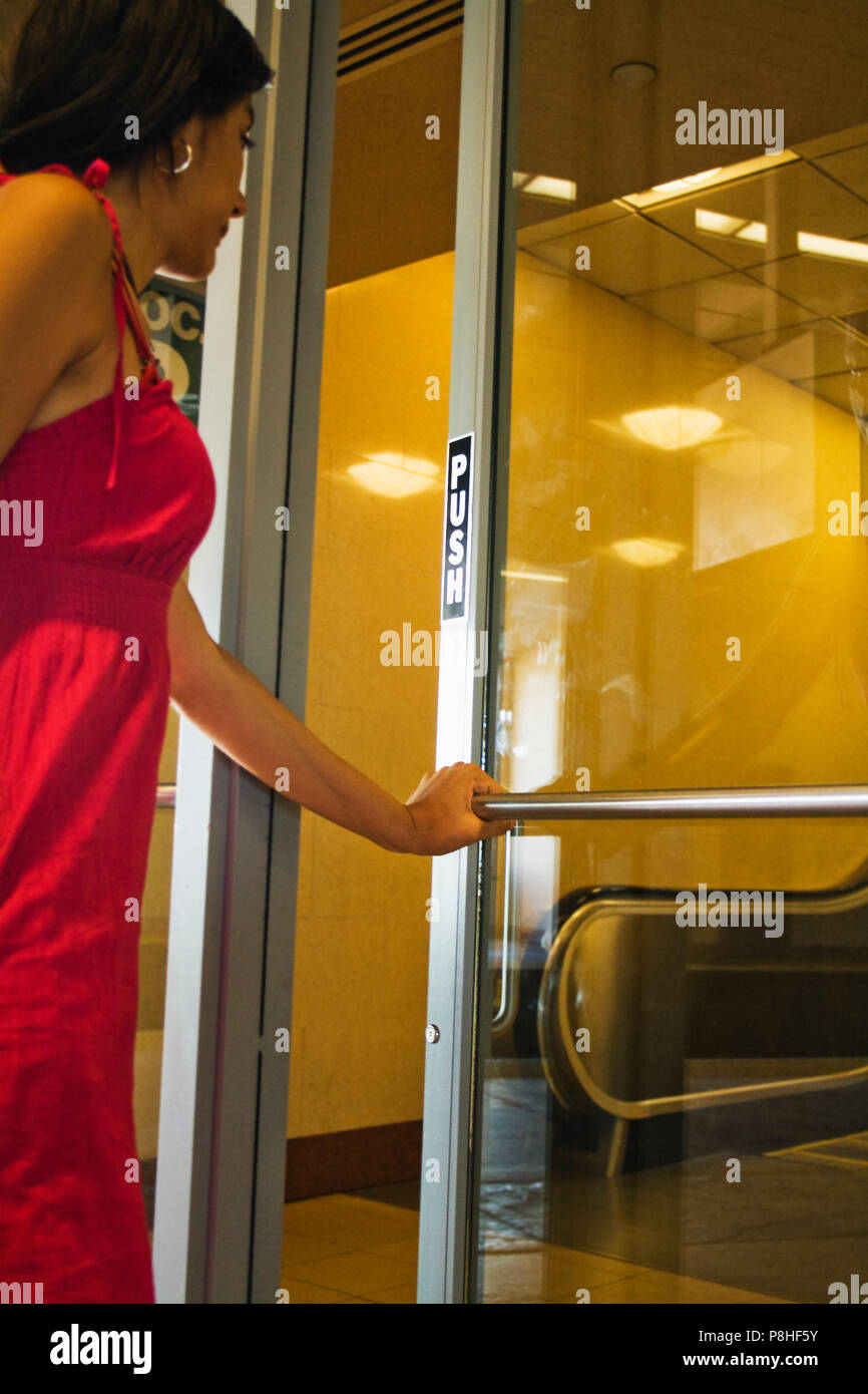 Young woman opening a glass door Stock Photo Alamy