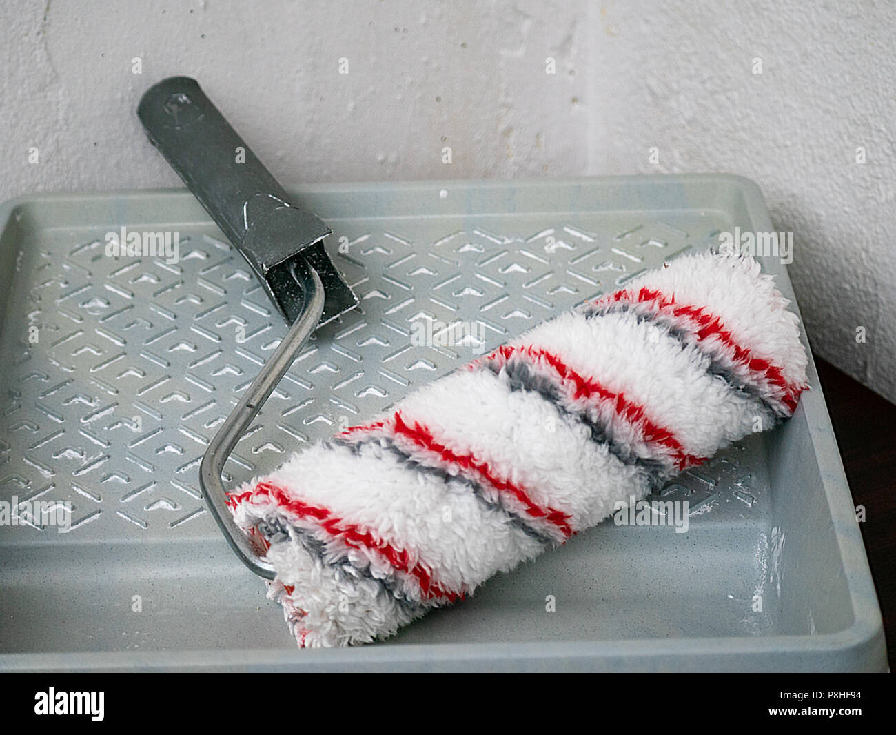 paint roll brush and white paint in plastic tray, house renovation concept Stock Photo