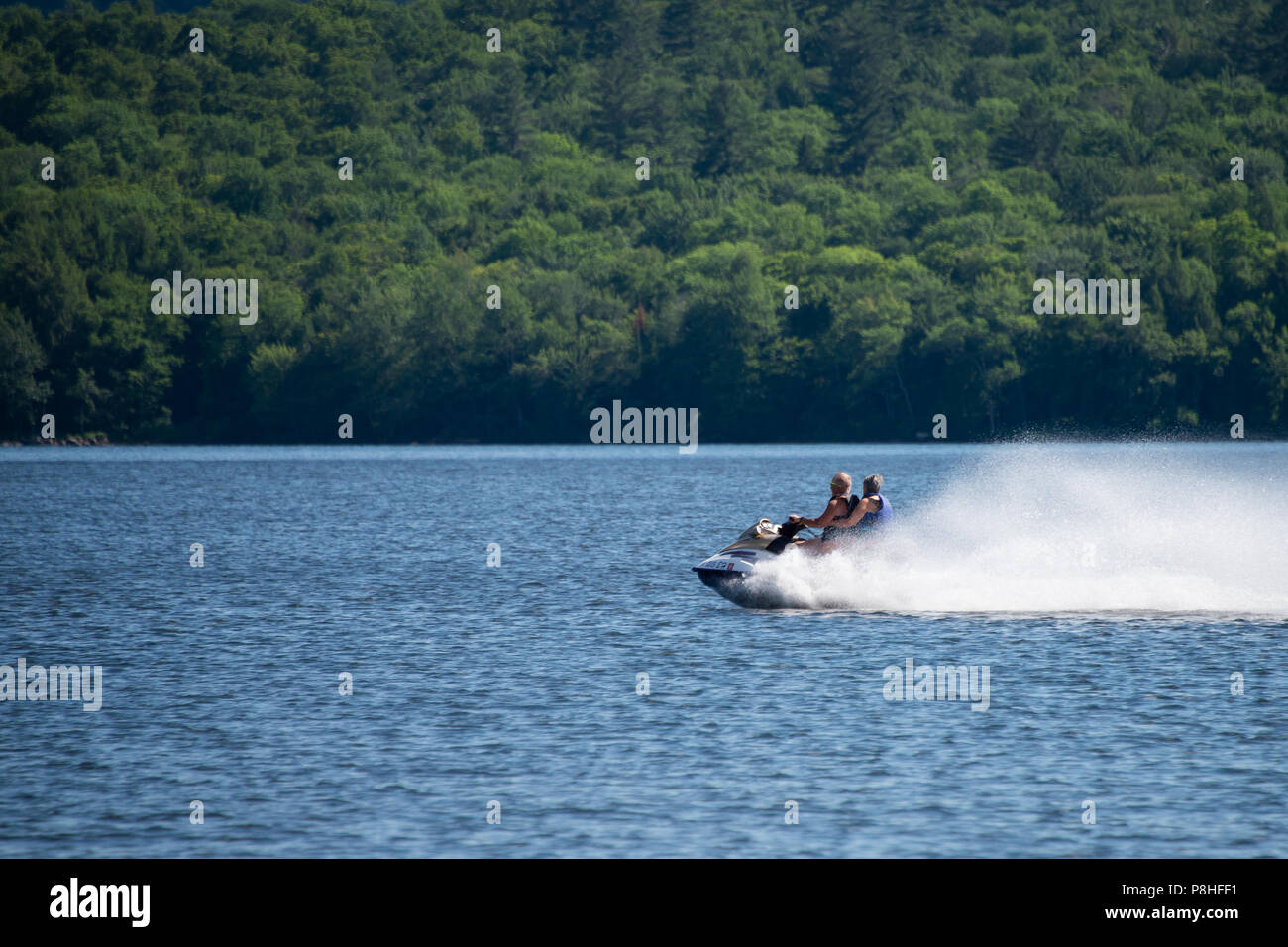 A fast jet propelled personal watercraft skimming over the water on Lake Pleasant, NY in the Adirondack Mountains. Stock Photo