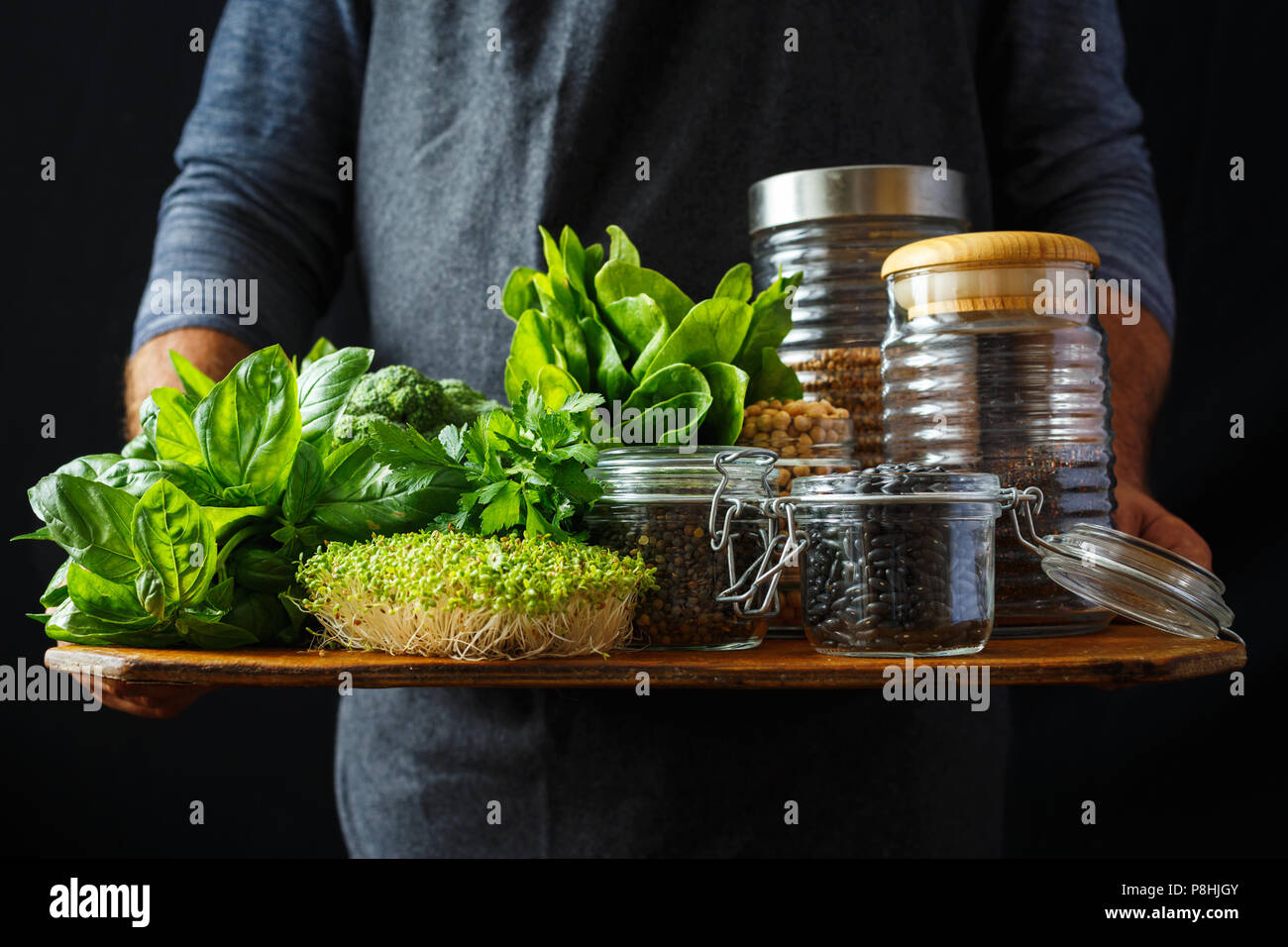 Man holds set healthy food, protein source for vegetarians: spinach, basil, parsley, broccoli, quinoa, black beans, green lentils, chickpeas and buckw Stock Photo
