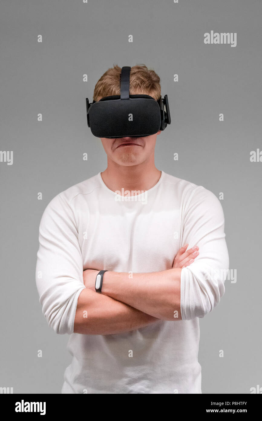 Man wearing virtual reality goggles on gray background. Student using VR headset. Stock Photo