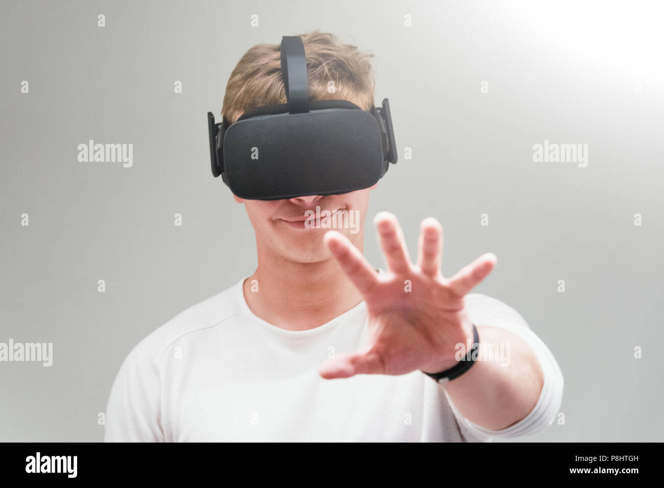 Man wearing virtual reality goggles on gray background. Student using VR headset. Stock Photo