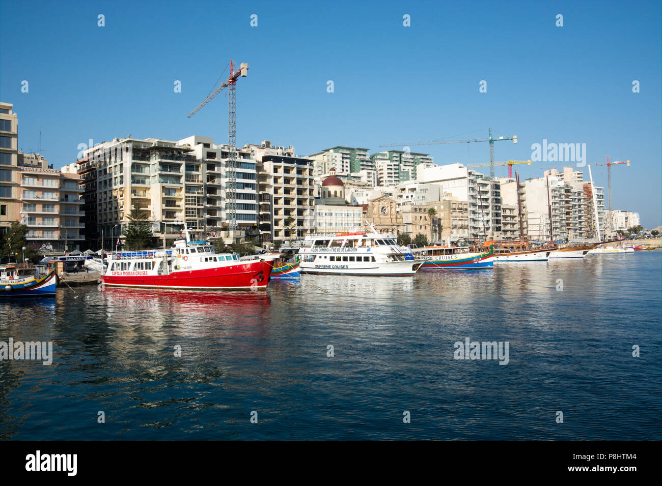 Sightseeing boats line the edge of Marsamxett Harbour in front of the ever changing Sliema skyline Stock Photo