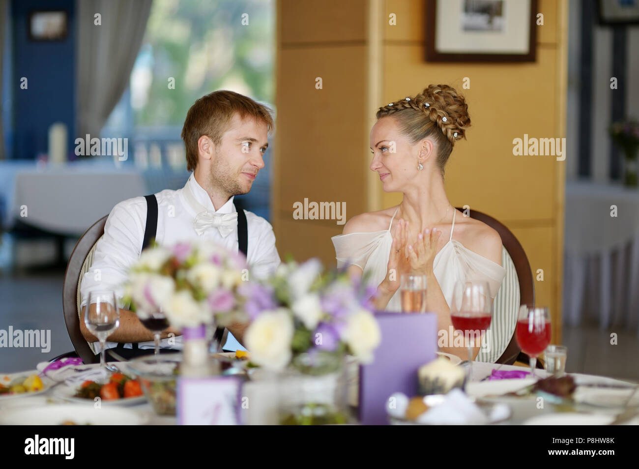 Happy bride and groom at the reception table Stock Photo - Alamy