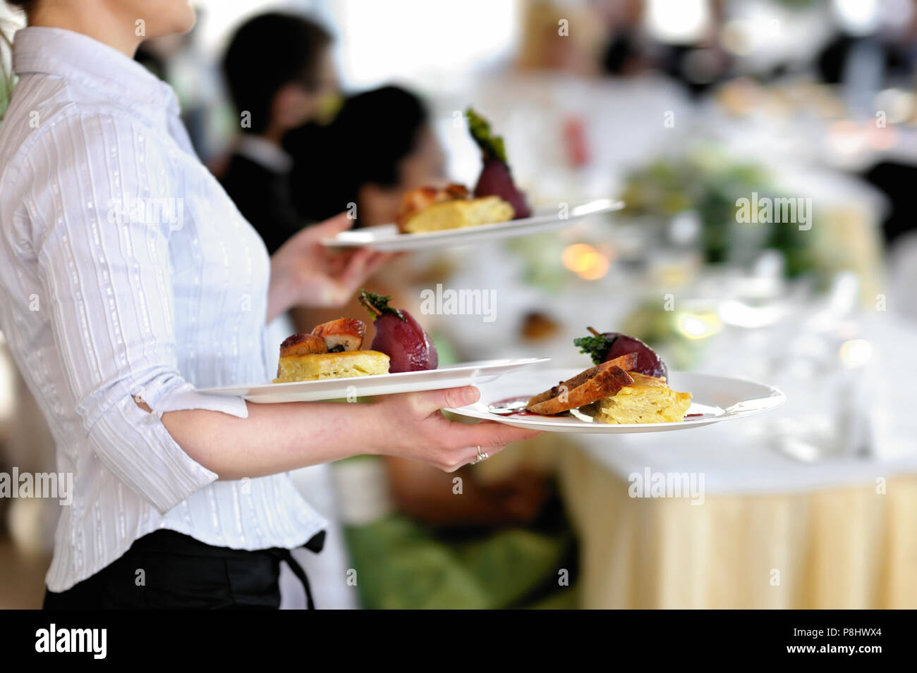 Waitress carrying three plates with meat dish Stock Photo Alamy