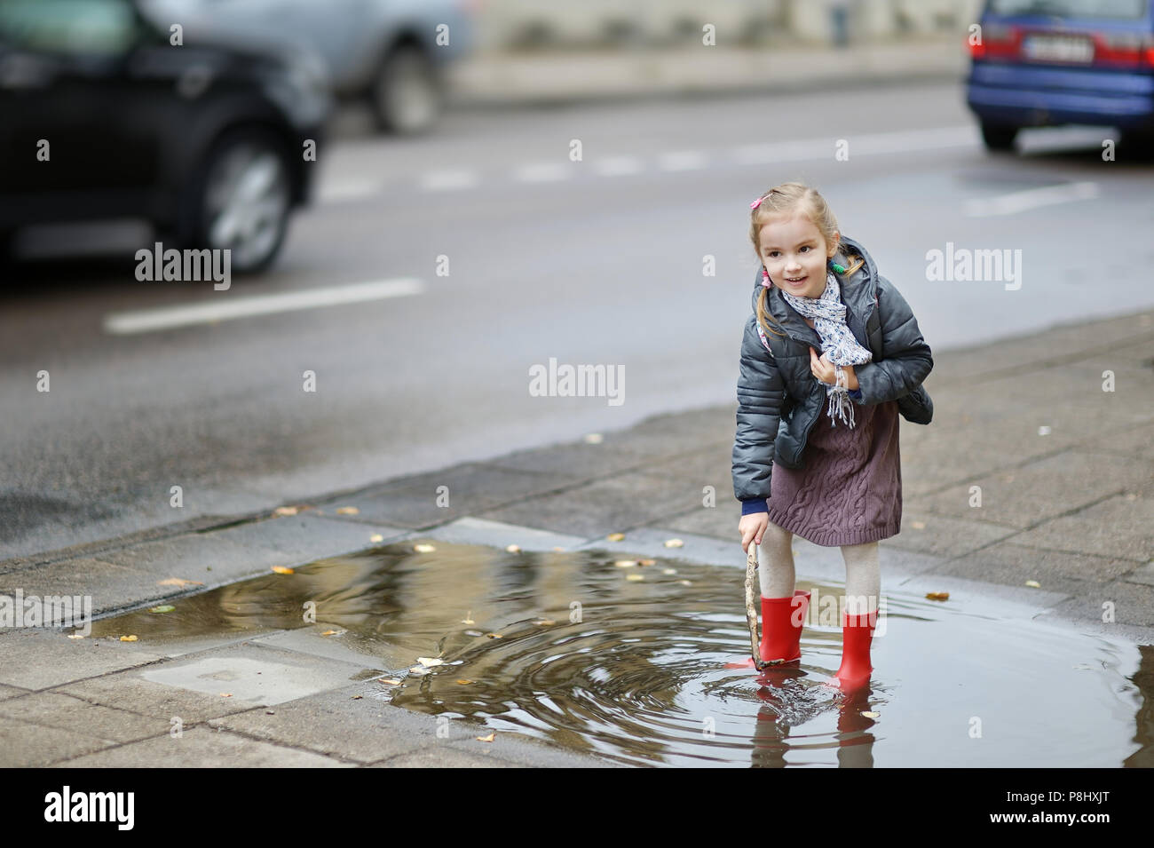 Adorable girl standing in a puddle on a rainy day at autumn Stock Photo ...