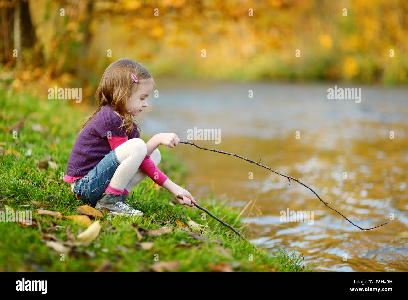 Adorable little girl playing by a river on autumn day Stock Photo - Alamy