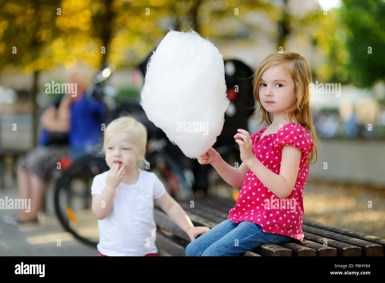 Adorable little girl eating candy-floss outdoors at summer Stock Photo ...