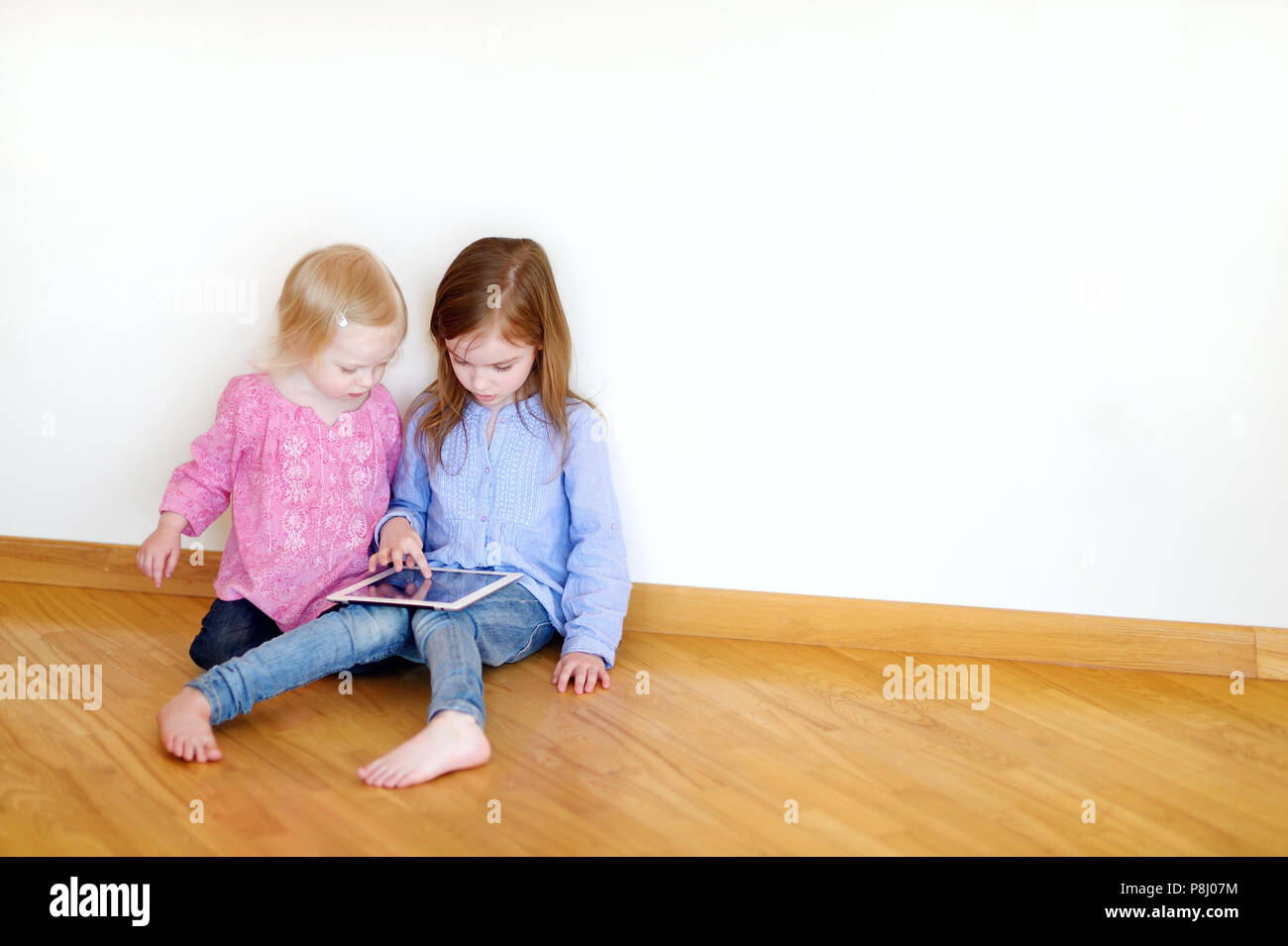 Two children playing on a digital tablet at home Stock Photo - Alamy