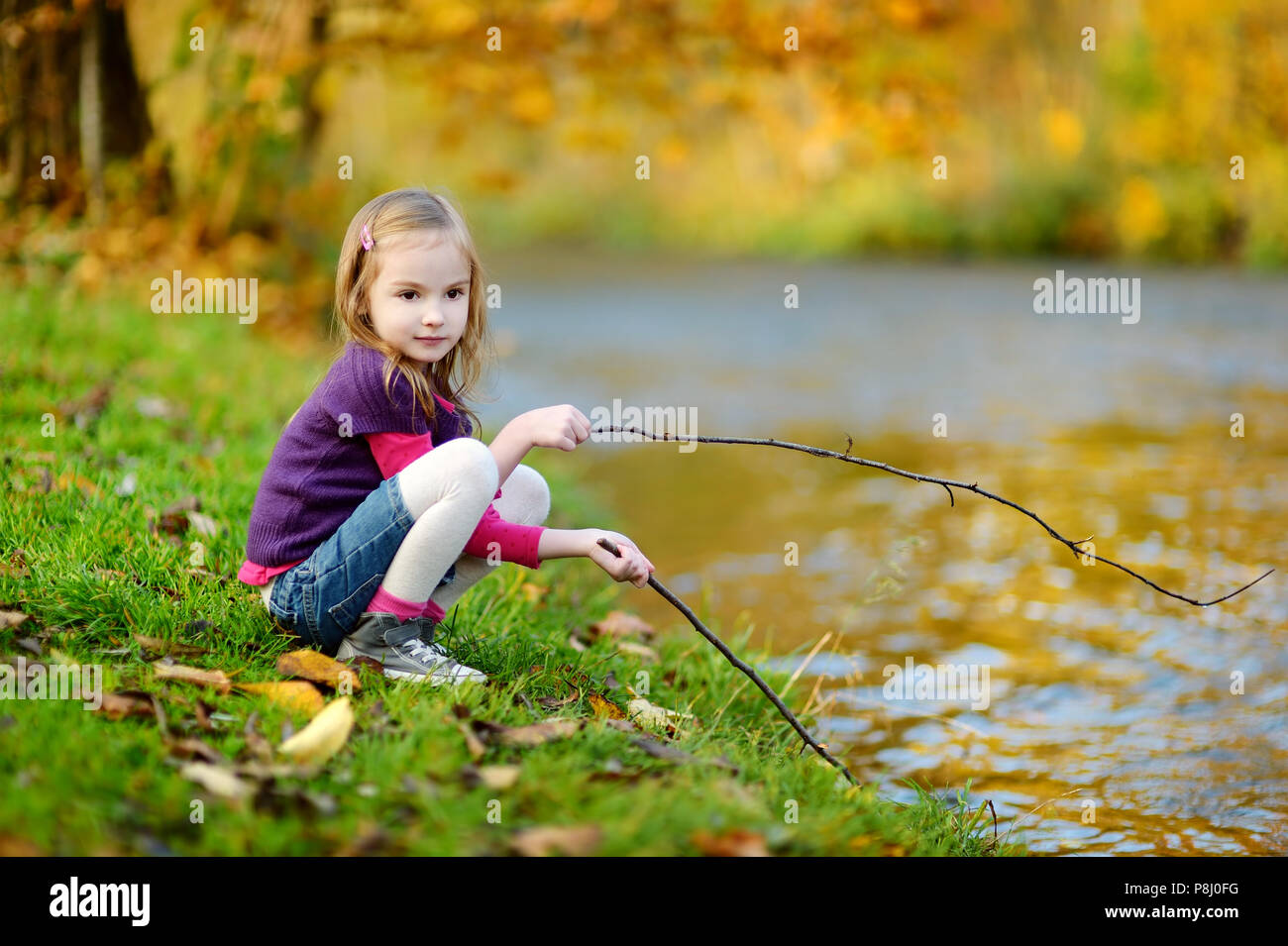 Adorable little girl playing by a river on autumn day Stock Photo - Alamy