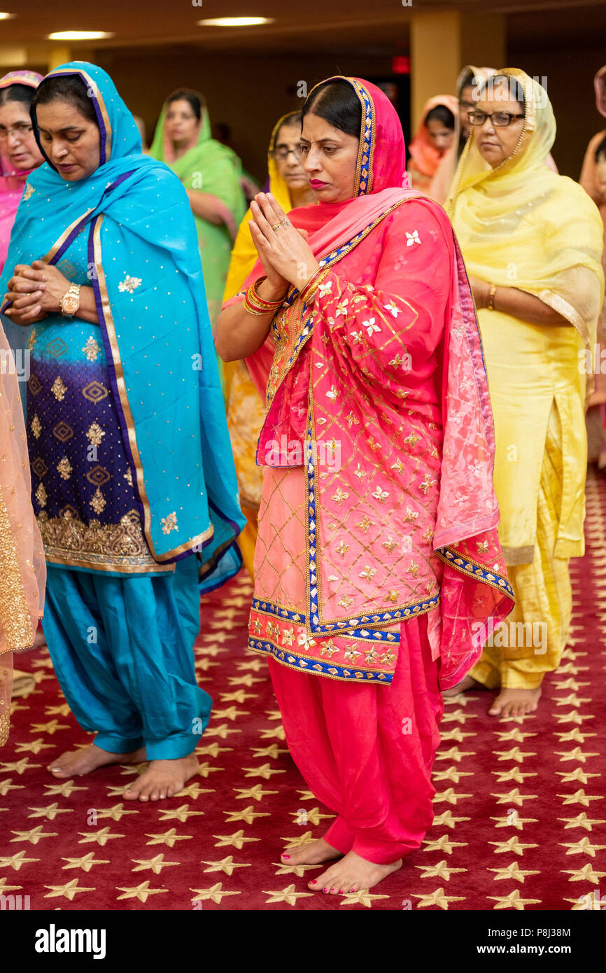 A group of women praying & meditating as guests at a wedding ceremony in the temple at the Sikh  Society in Richmond Hill, Queens, New York City. Stock Photo