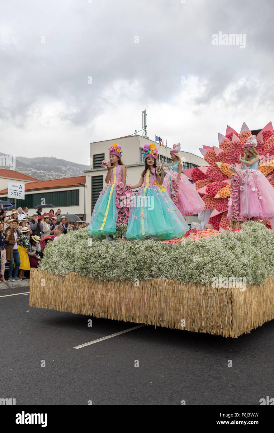 Funchal; Madeira; Portugal - April 22; 2018: Girls in colorful costumes on the floral float at Madeira Flower Festival Parade in Funchal on the Island Stock Photo