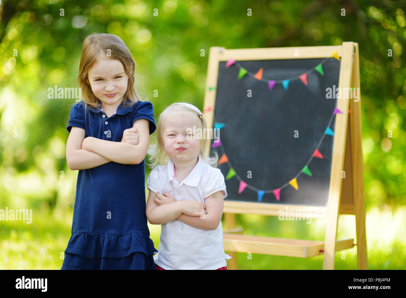 Two adorable sisters feeling unhappy about going back to school Stock Photo